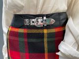 a woman wearing a plaid skirt and a belt