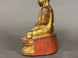 statue of a person sitting on a block with a red base