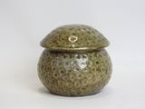 a small green pot with a lid on a white surface
