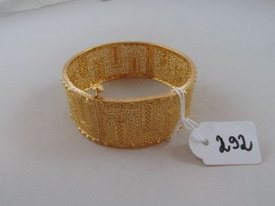 gold bracelet with a price tag on it sitting on a white surface