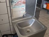 a stainless steel sink in a kitchen with a fire extinguisher next to it