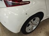 the rear end of a white car with scratches on the side of it