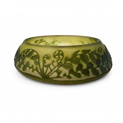 un bol vert orné de fleurs, posé sur une surface blanche