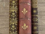 trois vieux livres sont empilés les uns sur les autres sur une table en bois