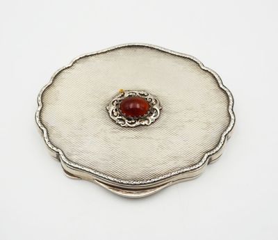 a close up of a silver plate with a red stone in it