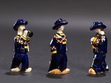 three figurines of a man and a woman dressed in blue and yellow