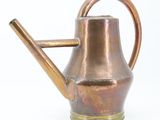 a copper watering can with a wooden handle on a white background