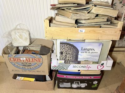 une pile de livres posée par terre à côté d'une pile de cartons