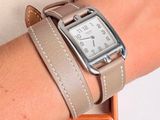 a woman wearing a watch on her wrist with a purse in the background