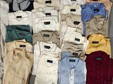a lot of men ' s shirts and pants laid out on a table