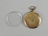 a close up of a gold pocket watch on a white surface