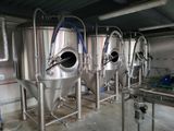 many stainless steel tanks lined up inside of a building