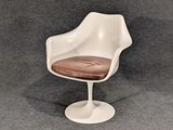 une photo d'une chaise blanche avec une assise marron posée sur un tapis gris