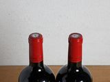 two bottles of red wine sitting on a table