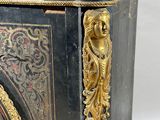a black and gold cabinet with a clock on top of it