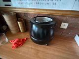 une cafetière noire posée sur une table en bois, à côté d'une tasse de café