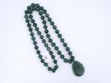 un gros plan sur un collier de perles vertes orné d'un pendentif en forme de feuille