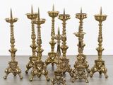 a set of six brass candlesticks on a wooden floor