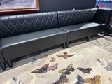a black leather bench in a room with a picture on the wall