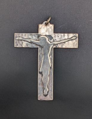 a silver cross with a jesus on it on a black background