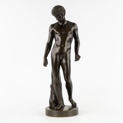 une statue en bronze représentant un homme debout sur un socle