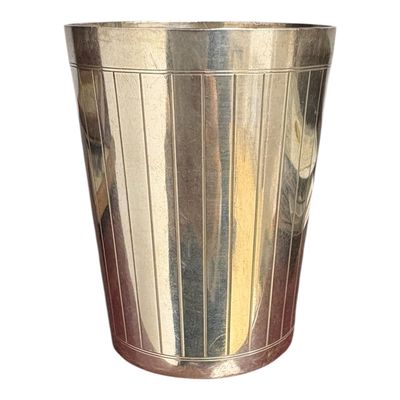 une tasse en métal posée sur une surface blanche