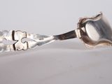 a silver spoon with a flower on it sitting on a table