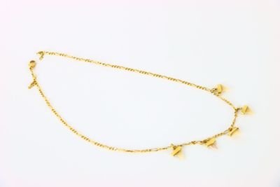 gros plan d'un collier en or sur une surface blanche