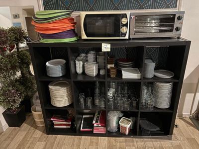 un micro-ondes posé sur une étagère où se trouvent des assiettes et des verres