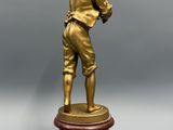 une figurine antique en bronze représentant un homme tenant une batte de baseball