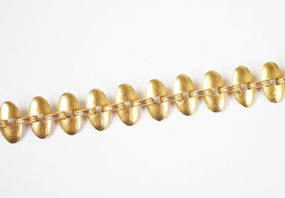 a close up of a row of gold colored beads on a white surface