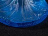a blue glass figurine of a woman on a black surface