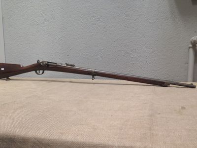 the rifle is sitting on the table next to the wall