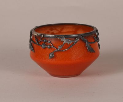 a small orange bowl with a metal decoration on it