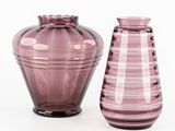 des vases en verre violet posés les uns à côté des autres sur une surface blanche