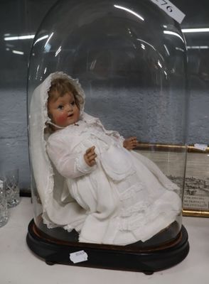 une cloche en verre posée sur une table, avec une poupée à l'intérieur