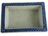 a small blue and white square bowl on a white surface