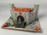 a toy castle with a red roof on a white surface