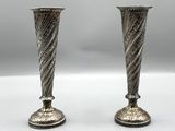 deux vases en argent posés l'un à côté de l'autre sur une table blanche