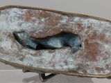 a bronze sculpture of a dog in a bowl on a stand