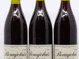 trois bouteilles de vin rouge sont alignées sur une surface blanche