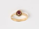 une bague en or avec une pierre rouge au centre