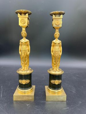 deux vases dorés et noirs ornés de statuettes, posés sur une table