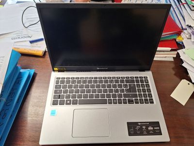 a laptop that is sitting on a desk in front of a pile of papers