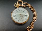 un gros plan d'une montre de poche en or attachée à une chaîne