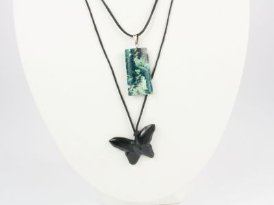 un collier noir et vert orné d'un pendentif en forme d'oiseau, porté par un mannequin blanc