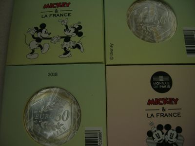 Quatre pièces différentes à l'effigie de Mickey et Minnie sont posées sur une table