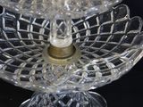 a three tiered glass cake stand with a candle on top