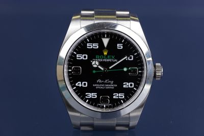 rolex watch with a black dial and green hands on a blue background