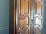 a wooden armoire in the corner of a room